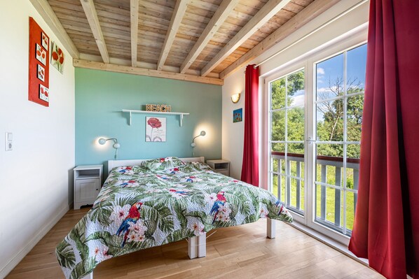 A bedroom with a bed, a window with a view, a shelf with a sign, and a nightstand.