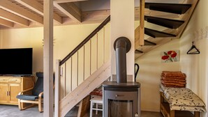 Ein gemütliches Zimmer mit einer Holztreppe, einem Kamin, einem Fernseher und einem Sofa.