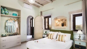 A bedroom with a bed, a wardrobe, a nightstand, a lamp, and a view of the outdoors. - 3-bed Armeni Mountain Oasis (Rethymno)