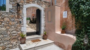 A stone building with a stone wall, a doorway, and steps leading to a door. - 3-bed Armeni Mountain Oasis (Rethymno)