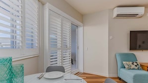 Un coin repas avec une table dressée pour quatre personnes, un canapé et un téléviseur fixé au mur.