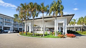 Un hôtel doté d’un espace extérieur abrité, de palmiers et d’une enseigne indiquant le nom de l’hôtel.
