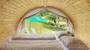 Ein Zelt mit Bett, Kissen und einem grünen Sonnenschirm.