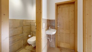 Een badkamer met toilet, wastafel en houten deur.
