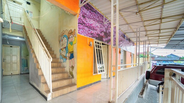 A building with a staircase, a mural, and a covered area with a car parked outside. - Sunrise 888 By ARBA (Semarang)
