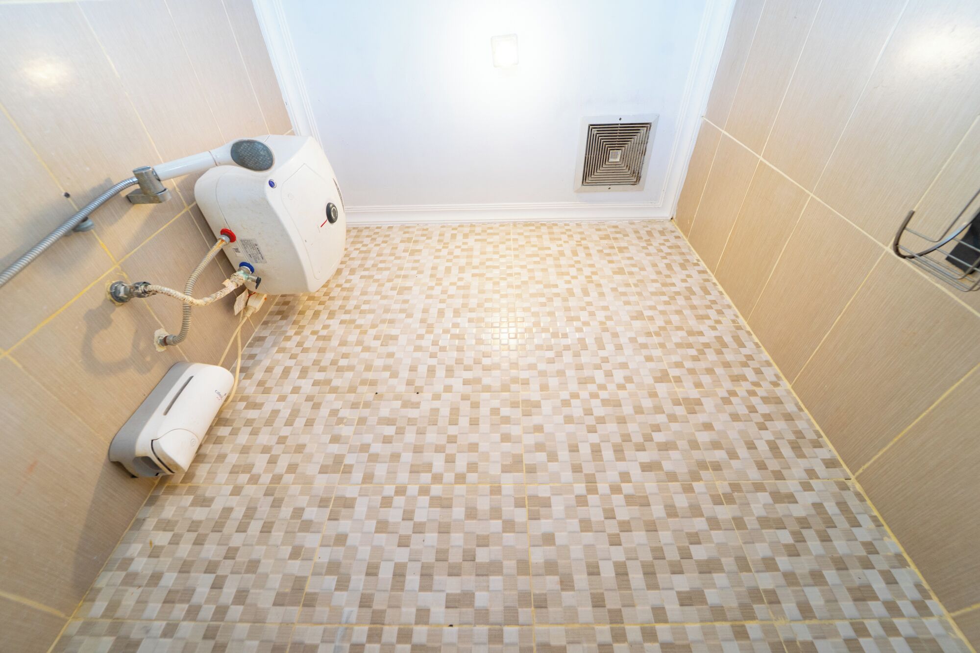 Casa de banho com chão xadrez, chuveiro e ventilação.
