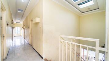 A corridor with a tiled floor, a white railing, and a skylight.