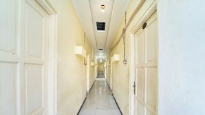 A hotel hallway with doors on both sides, a tiled floor, and overhead lighting. - Sunrise 888 By ARBA (Semarang)