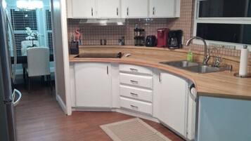 A kitchen with white cabinets, a wooden countertop, a sink, and a window.