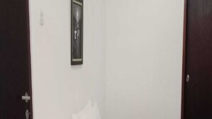 A small, single-bed room with a wooden headboard, white bedding, and a gray blanket. - Cozzy Villa Pangi (Bandung)