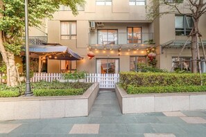 A building with a white picket fence, a covered outdoor seating area, and a balcony with string lights. - Masteri Thao Dien Apartment Raymond Holm (An Khanh)