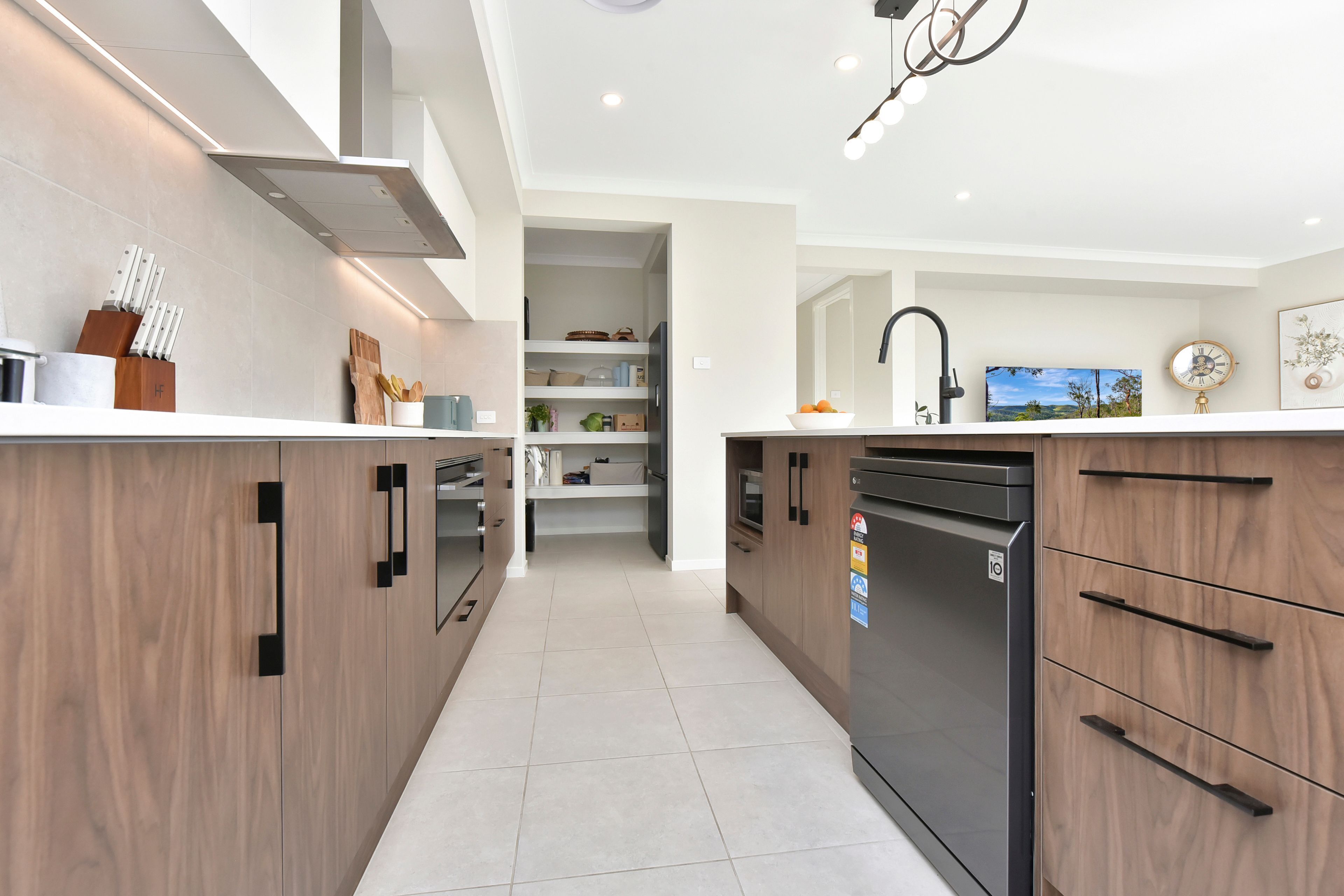 A modern kitchen with wooden cabinets, a black dishwasher, and a countertop with various items.