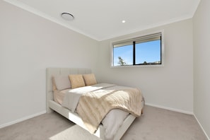 Ein Schlafzimmer mit Bett, Fenster und Deckenleuchte.