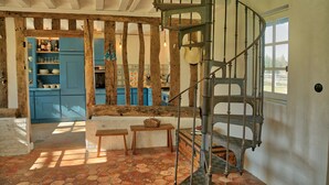 Eine rustikale Küche mit blauen Schränken, einer Wendeltreppe und einer Steinwand.