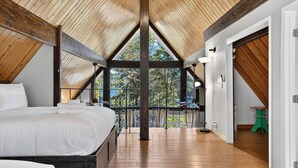 Un dormitorio con techo de madera, una cama y un balcón con vistas.