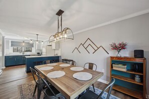 A modern kitchen with a dining area, wooden table, and chairs. - Indoor Pool + Sauna | Gore Mtn + North Creek | The Summit at Gore Mountain (North Creek)