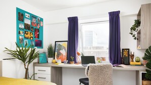 A modern bedroom with a bed, a desk with a laptop, a chair, and a window with curtains. - Student Only - Ty Pont Haearn - Cardiff (Cardiff)