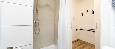 Un baño moderno con ducha, inodoro y perchero para toallas.