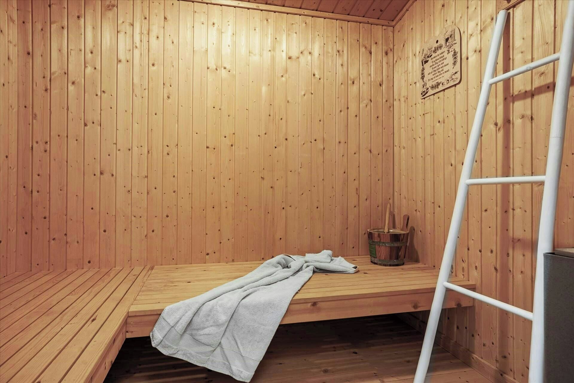 Een sauna met houten wanden, een bank, een handdoek en een trapje.