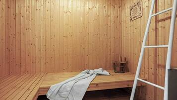 Een sauna met houten wanden, een bank, een handdoek en een trapje.