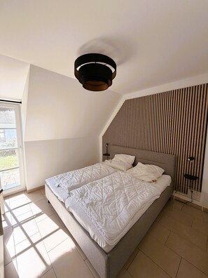 A bedroom with a bed, a window, and a sloped ceiling. - Blauer Peter Luxury Vacation Home with Fireplace and Sauna on Usedom (Zempin)