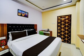 A hotel room with a bed, a desk, a chair, a picture on the wall, and a door with a floral pattern. - Hotel O Hafizpet Railway Station (Hyderabad)
