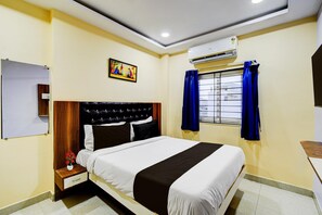 A hotel room with a bed, a nightstand, a wall-mounted air conditioner, a window with curtains, and a painting on the wall. - Hotel O Hafizpet Railway Station (Hyderabad)