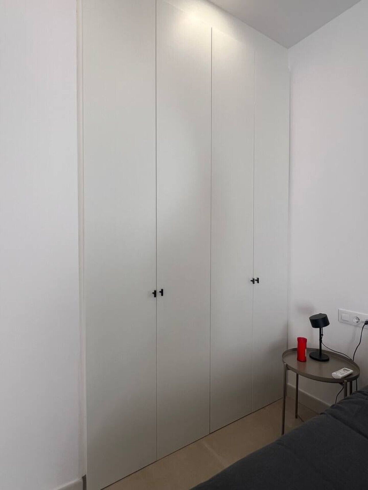 Un dormitorio con cama, una mesita de noche con lámpara y un armario.