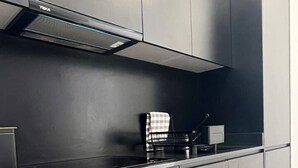 Une cuisine moderne dotée d’un four encastré, d’un four à micro-ondes et d’un plan de travail noir.