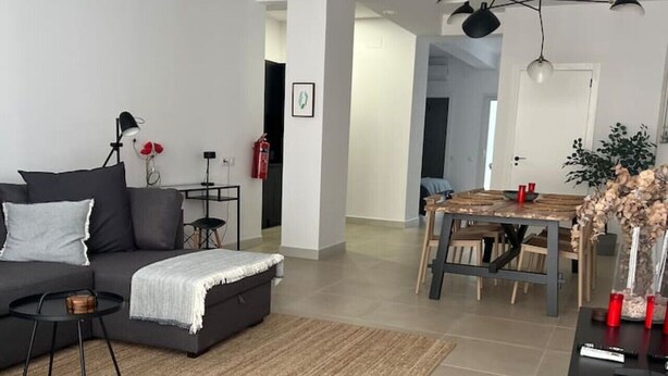 Un salon moderne comprenant un canapé, une table basse, un tapis et un coin repas avec une table et des chaises.