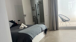 Une chambre moderne avec un lit, une douche et un balcon équipé d’une chaise.