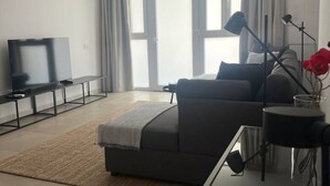 Un salon moderne avec un canapé, une table basse en verre et un téléviseur.