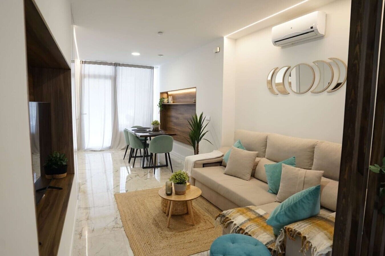 A modern living room with a sofa, coffee table, and dining area with chairs.