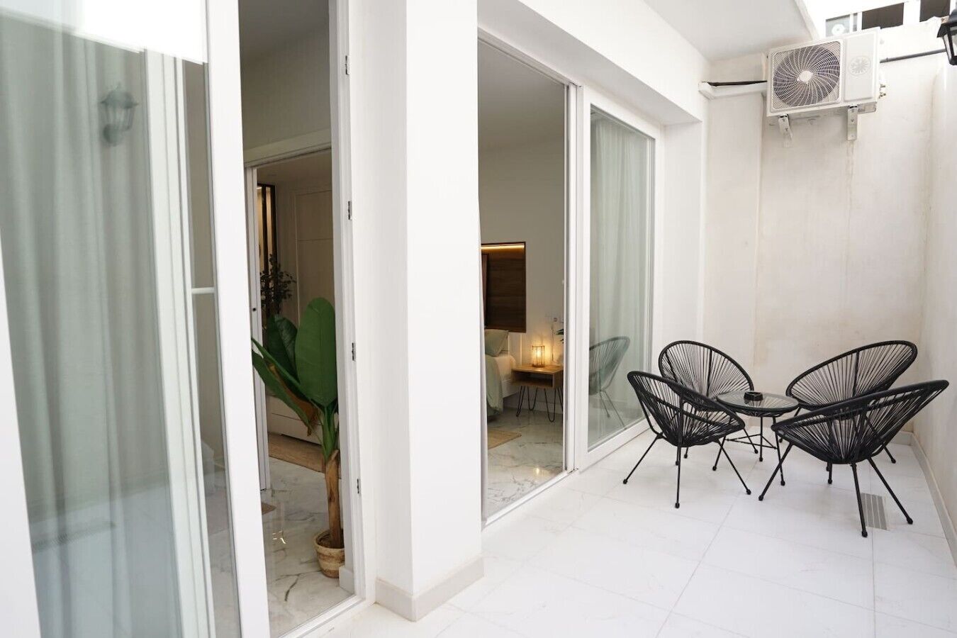 A modern interior with a dining area, a sliding glass door leading to a balcony, and an air conditioning unit mounted on the wall.