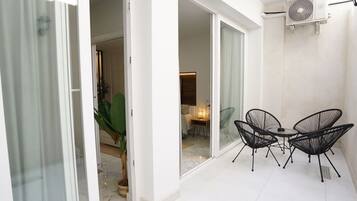 A modern interior with a dining area, a sliding glass door leading to a balcony, and an air conditioning unit mounted on the wall.