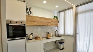 Eine kompakte Küche mit Backofen, Spüle und Mülleimer.