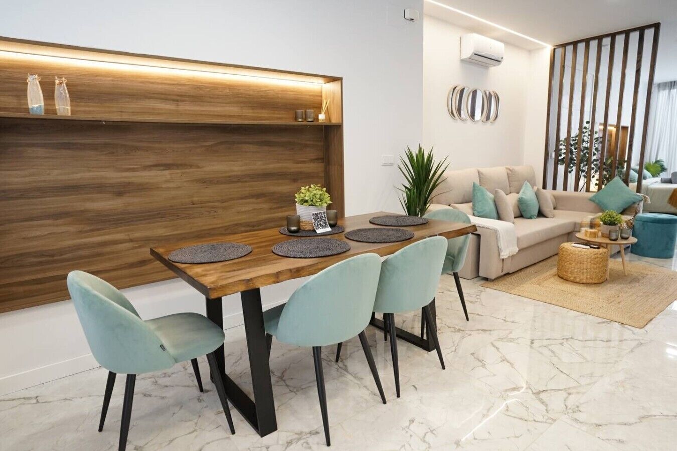 A modern living room with a dining area, a sofa set, and a decorative wall.