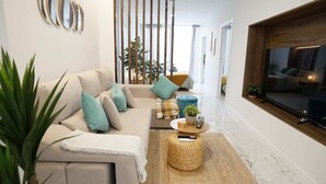 Ein modernes Wohnzimmer mit einer Couch, einem Fernseher und einer Pflanze.