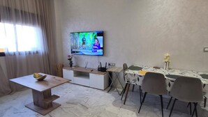 A modern living room with a TV, dining table, chairs, and a sofa.