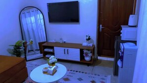A living room with a sofa, a coffee table, a TV, a cabinet, and a refrigerator.