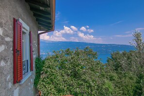 Un bâtiment avec des volets rouges, une vue sur la mer et un feuillage dense.