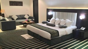 Ein Hotelzimmer mit einem großen Bett, einer Schlafcouch, einem Nachttisch mit Telefon und einem Wandbild.