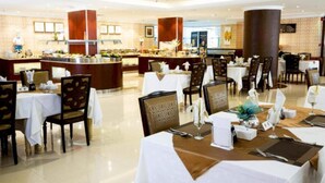 Ein Hotel-Essbereich mit mehreren gedeckten Tischen für Gäste, einer Buffetstation und einer großen Säule in der Mitte.