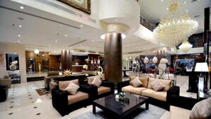 Eine geräumige Lobby mit hoher Decke, einem großen Chandelier und einer Rezeption.