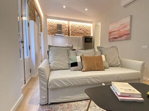 Ein modernes Wohnzimmer mit Sofa, Couchtisch und einer Küche im Hintergrund.