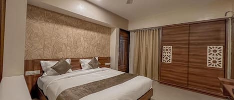 A hotel room with a bed, a ceiling fan, a wardrobe, and a desk.