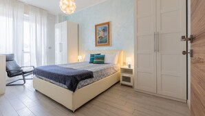 Een slaapkamer met een bed, nachtkastjes, een stoel, een garderobe en een schilderij aan de muur.