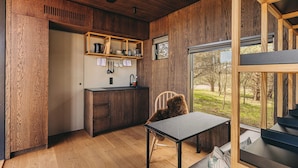 A compact kitchen with wooden cabinetry, a sink, and a window overlooking a grassy area. - Curlew (St. Andrews)