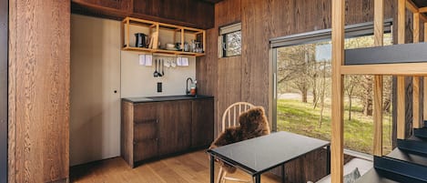 A modern kitchen with wooden cabinetry, a built-in sink, and a window overlooking a grassy area.