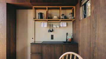 A compact kitchen with wooden cabinetry, a black countertop, and a window with a view.